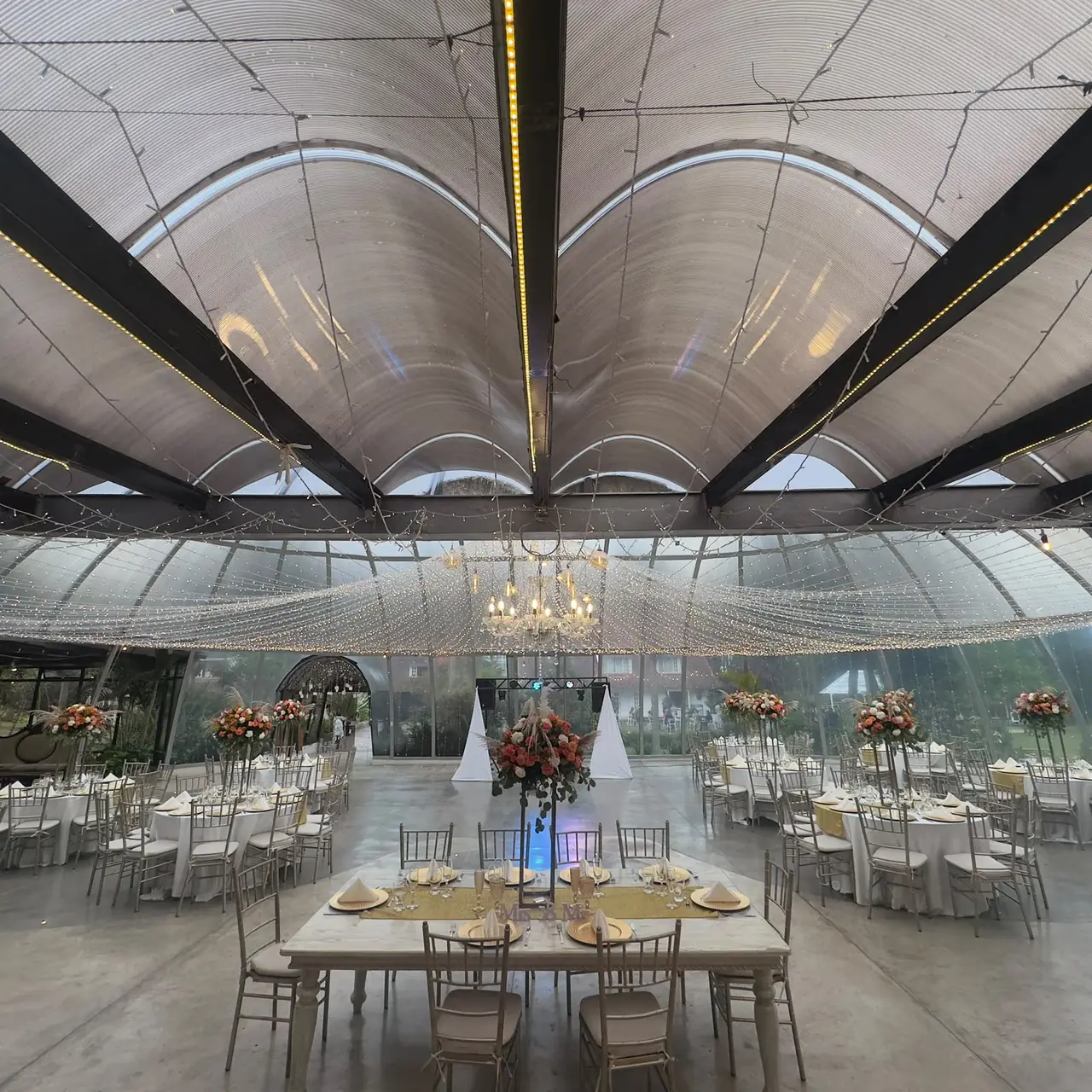 Montaje de boda en carpa de cristal con candelabros, mesas vestidas y sillas Chiavari