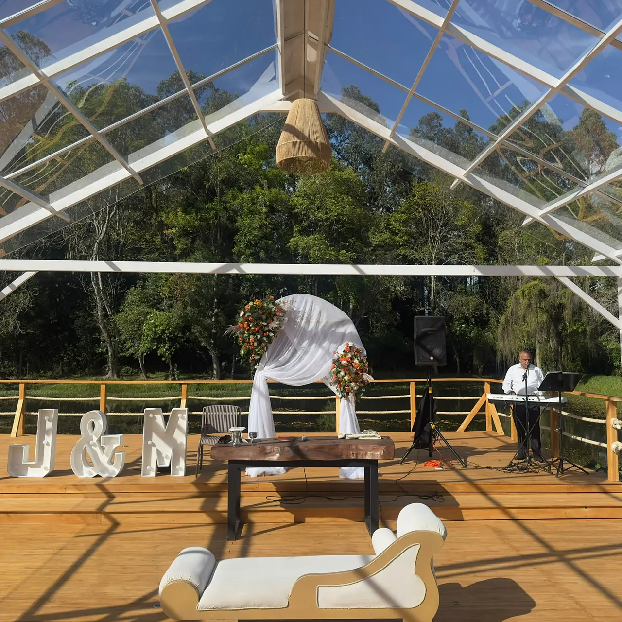 Ceremonia en terraza de madera con arco floral y letras de los novios