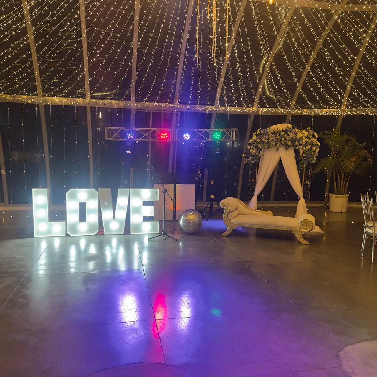 Letras LOVE iluminadas, luces robóticas y techo de luces cálidas