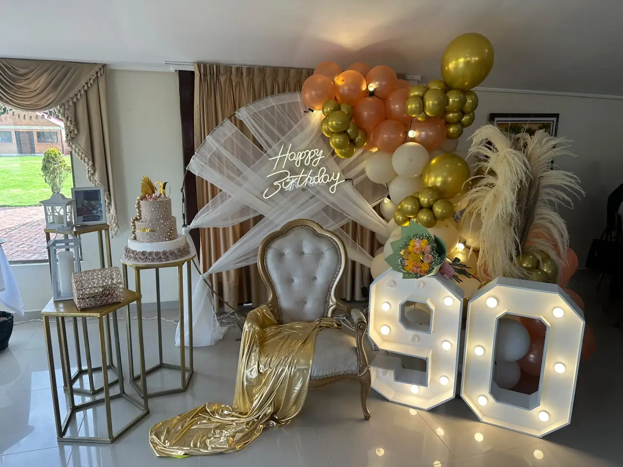 Celebración de 90 años con globos dorados y números luminosos