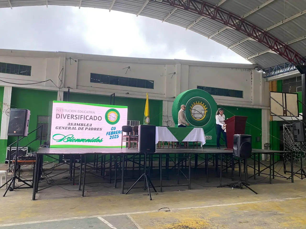 Evento institucional en colegio con tarima, sonido y pantalla
